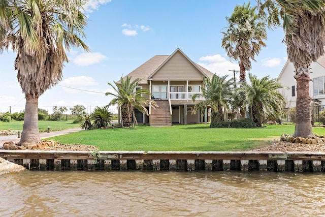 rear view of property featuring a balcony, a yard, and a water view