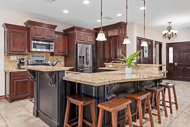 kitchen with tasteful backsplash, pendant lighting, appliances with stainless steel finishes, a large island, and a chandelier