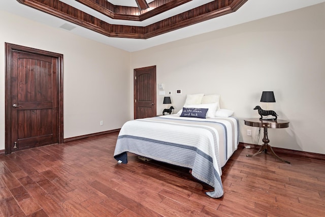 bedroom featuring dark hardwood / wood-style flooring, crown molding, and a tray ceiling