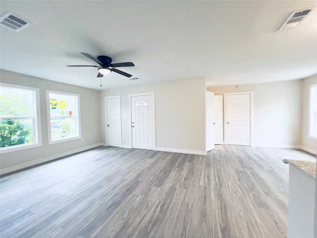 unfurnished room with light wood-type flooring, ceiling fan, and plenty of natural light