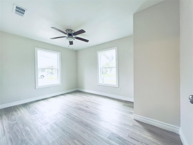 empty room featuring ceiling fan, a healthy amount of sunlight, and light hardwood / wood-style floors