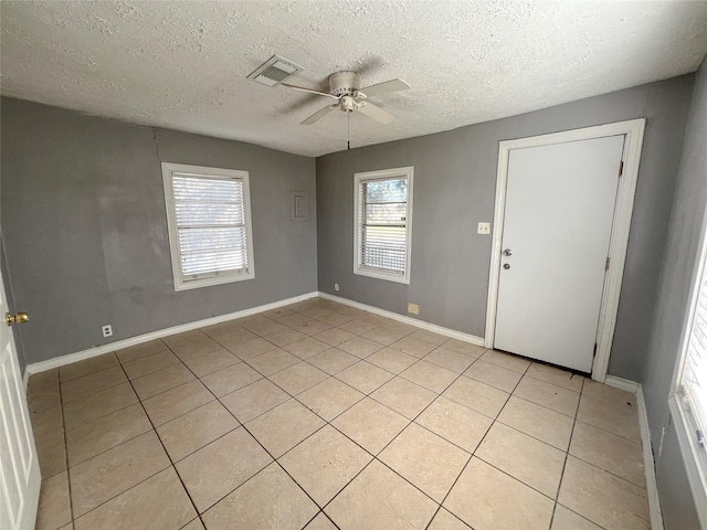 interior space with a textured ceiling, ceiling fan, and light tile patterned flooring