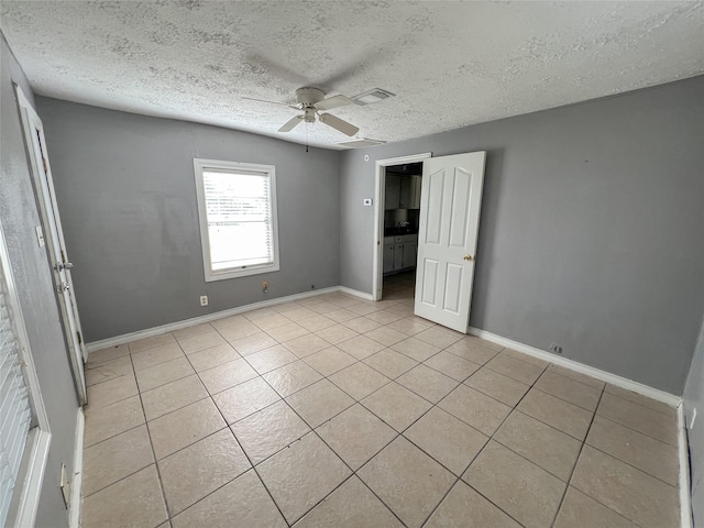 unfurnished bedroom featuring ceiling fan, a textured ceiling, and light tile patterned floors