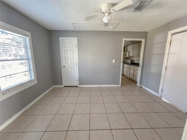 tiled spare room with ceiling fan and a textured ceiling