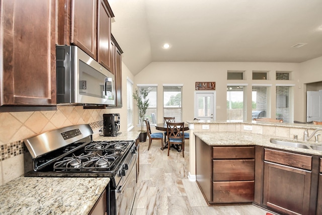 kitchen featuring appliances with stainless steel finishes, tasteful backsplash, sink, vaulted ceiling, and light stone counters