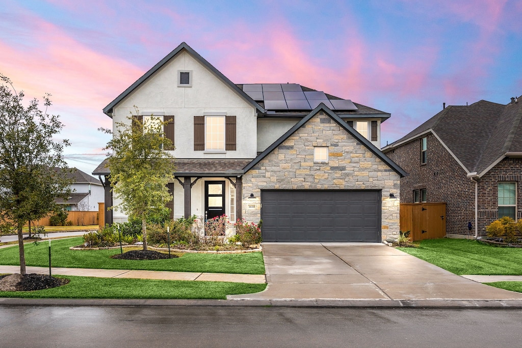 view of front of property with solar panels, a yard, and a garage