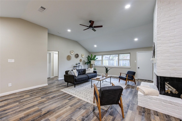 living room featuring vaulted ceiling, ceiling fan, a fireplace, and wood-type flooring