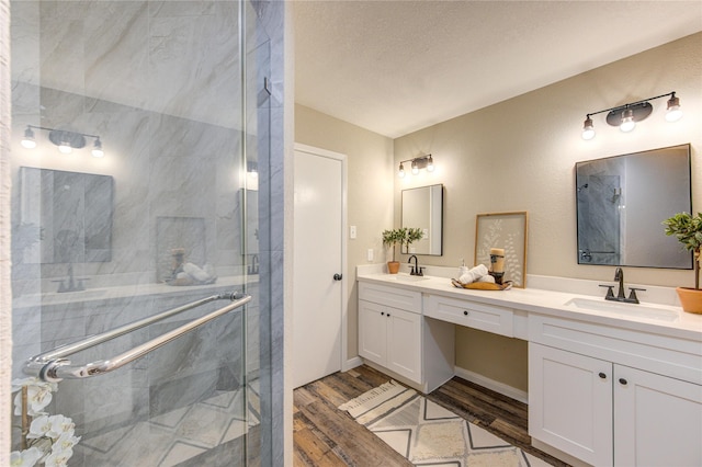 bathroom featuring a textured ceiling, a shower with shower door, wood-type flooring, and vanity