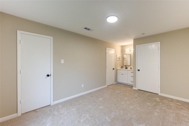 unfurnished bedroom featuring light colored carpet and connected bathroom