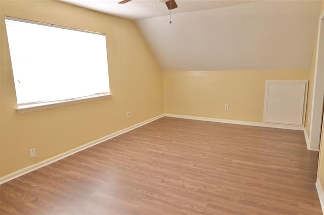 bonus room featuring a textured ceiling, ceiling fan, vaulted ceiling, and light hardwood / wood-style flooring