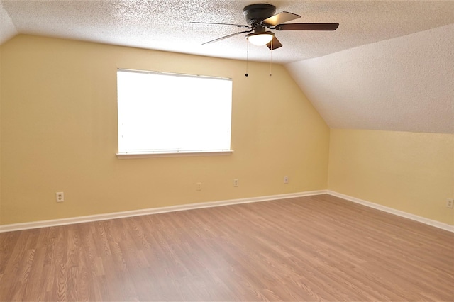 bonus room featuring light hardwood / wood-style floors, a textured ceiling, and vaulted ceiling