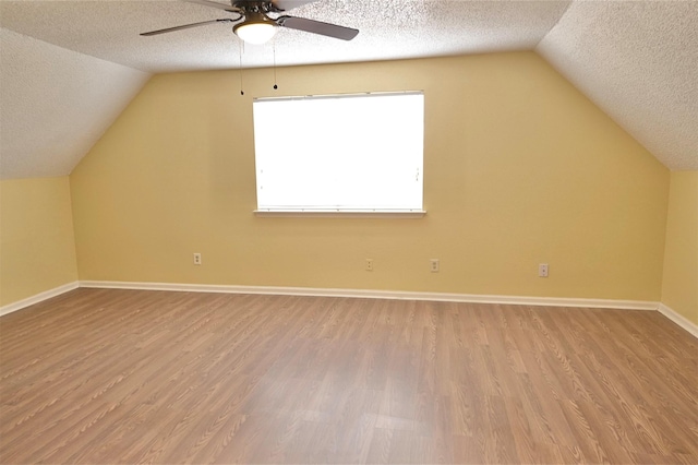 additional living space featuring a textured ceiling, vaulted ceiling, and light wood-type flooring