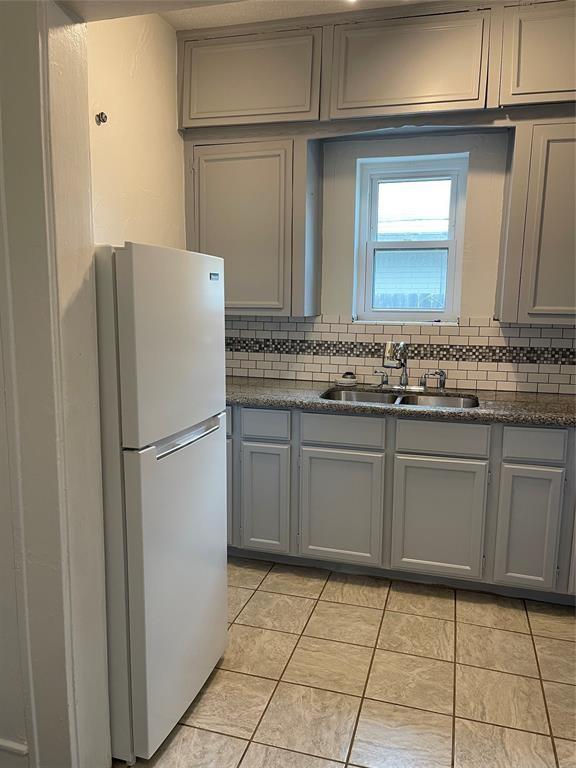 kitchen with white refrigerator, sink, backsplash, gray cabinets, and light tile patterned flooring