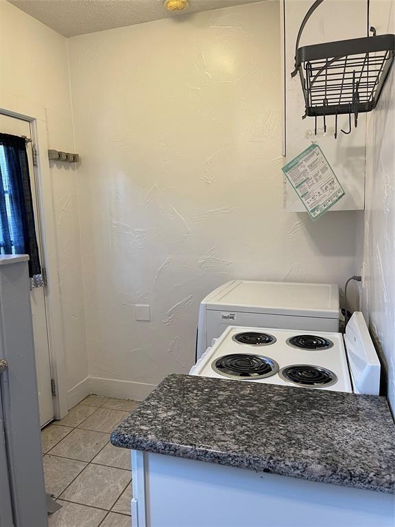 kitchen with electric range oven, a textured ceiling, and light tile patterned flooring