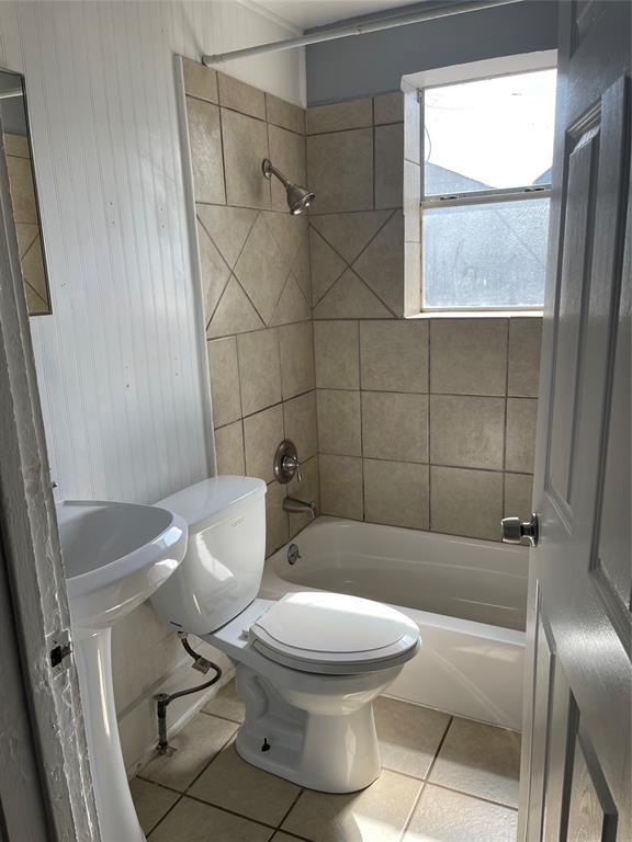 bathroom with toilet, tile patterned flooring, and tiled shower / bath combo