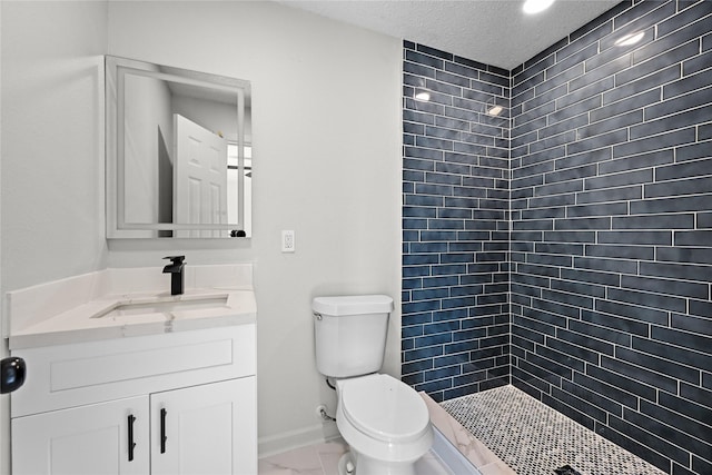 bathroom featuring a textured ceiling, tiled shower, vanity, and toilet