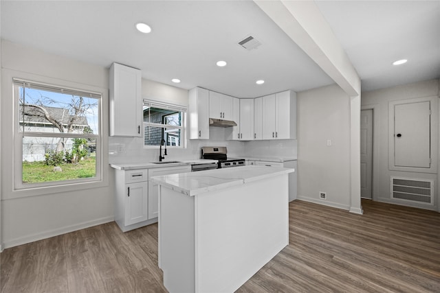 kitchen with stainless steel range with electric stovetop, white cabinetry, light hardwood / wood-style floors, sink, and a center island