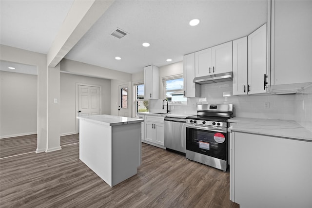 kitchen featuring stainless steel appliances, backsplash, a kitchen island, white cabinets, and sink