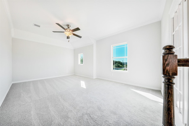 carpeted spare room featuring ornamental molding, baseboards, visible vents, and ceiling fan