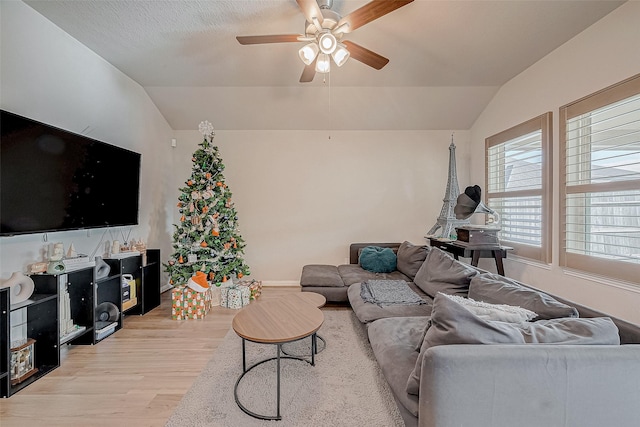 living room with ceiling fan, light hardwood / wood-style flooring, and vaulted ceiling