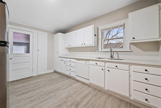 kitchen with lofted ceiling, white cabinetry, white dishwasher, and sink