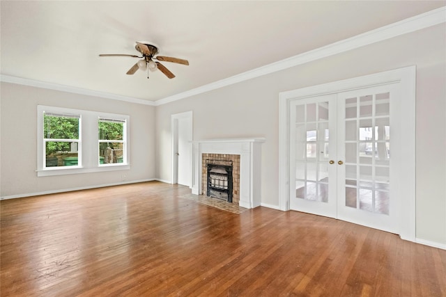 unfurnished living room with ceiling fan, a brick fireplace, hardwood / wood-style flooring, ornamental molding, and french doors