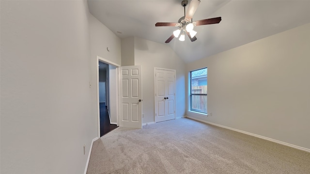 unfurnished bedroom featuring ceiling fan, lofted ceiling, and light colored carpet