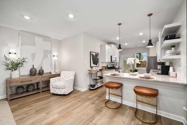 kitchen with light stone counters, backsplash, white cabinets, and appliances with stainless steel finishes