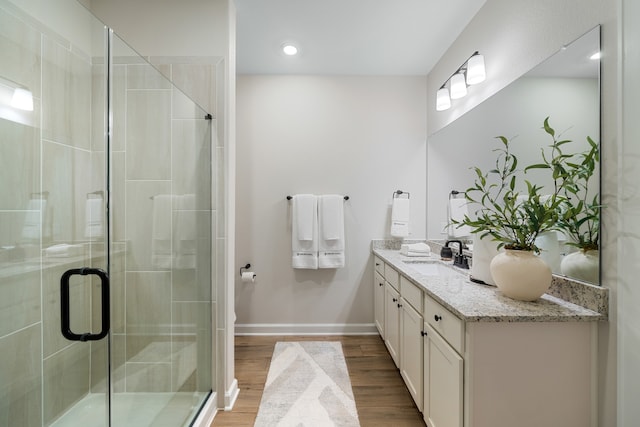 bathroom with hardwood / wood-style floors, walk in shower, and vanity