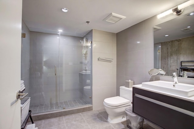 bathroom featuring tile patterned floors, vanity, tile walls, toilet, and walk in shower