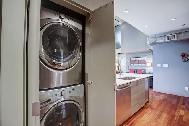 laundry room featuring stacked washer / drying machine, light hardwood / wood-style flooring, and sink