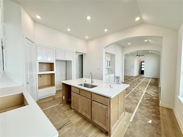 kitchen with a center island with sink, white cabinets, ceiling fan, vaulted ceiling, and sink