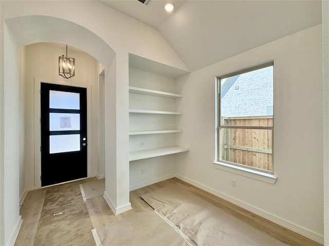 entryway featuring light wood-type flooring, vaulted ceiling, and an inviting chandelier