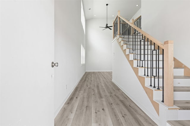 staircase with ceiling fan, a high ceiling, and hardwood / wood-style flooring