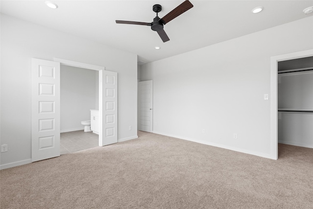 unfurnished bedroom with ensuite bathroom, ceiling fan, and light carpet