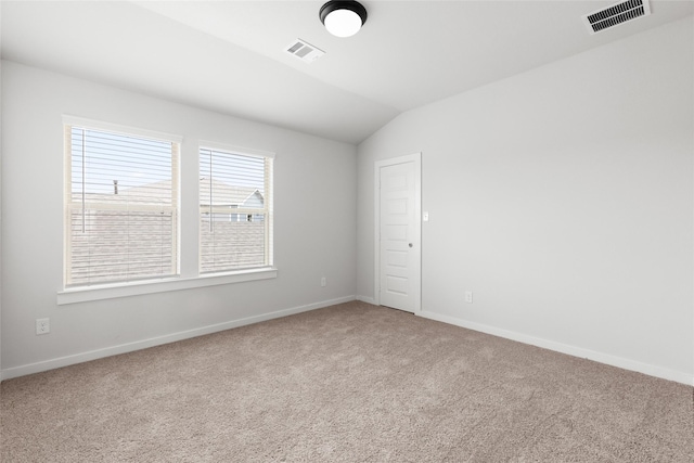 carpeted empty room with vaulted ceiling