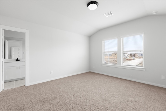 carpeted spare room featuring lofted ceiling and sink