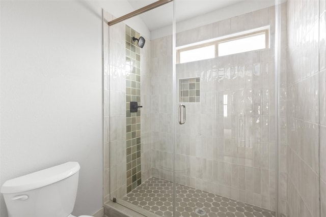 bathroom featuring toilet and a shower with shower door