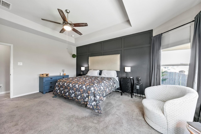 bedroom with ceiling fan, light colored carpet, and a raised ceiling