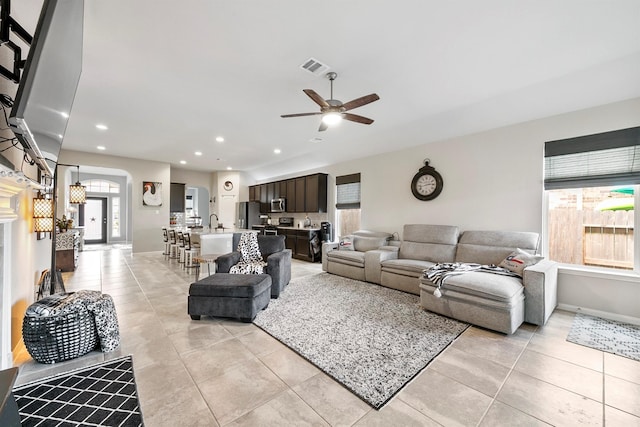 living room featuring ceiling fan, light tile patterned floors, and sink