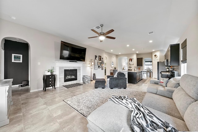 living room with ceiling fan and a tiled fireplace