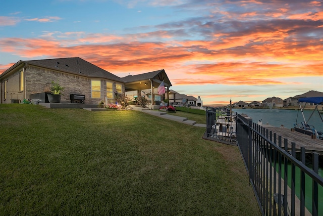 yard at dusk featuring a water view and a patio