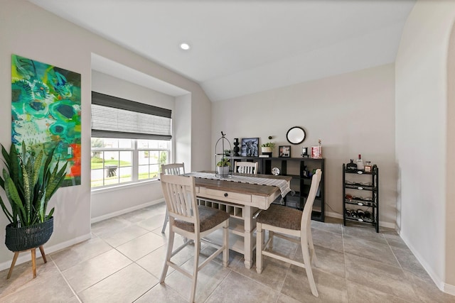 dining room with light tile patterned floors and vaulted ceiling