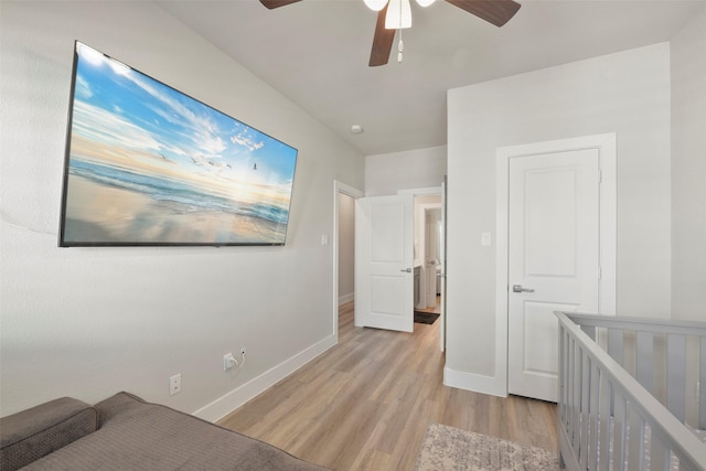 bedroom with ceiling fan, light hardwood / wood-style floors, and a crib