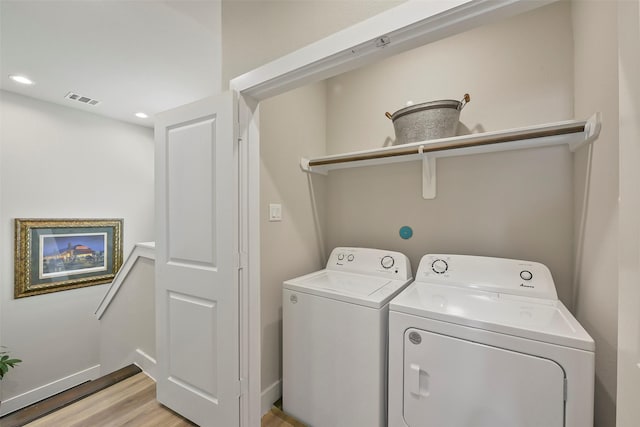 clothes washing area featuring separate washer and dryer and light hardwood / wood-style floors