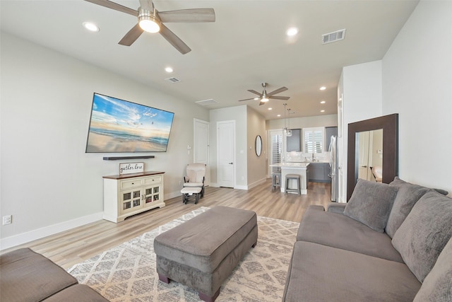 living room with ceiling fan, light hardwood / wood-style floors, and sink