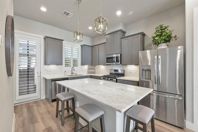 kitchen featuring a center island, decorative light fixtures, stainless steel appliances, sink, and backsplash