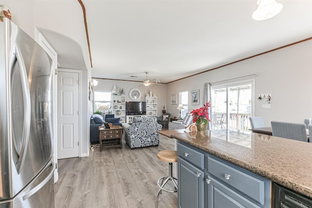 kitchen with ceiling fan, stainless steel fridge, ornamental molding, and light wood-type flooring