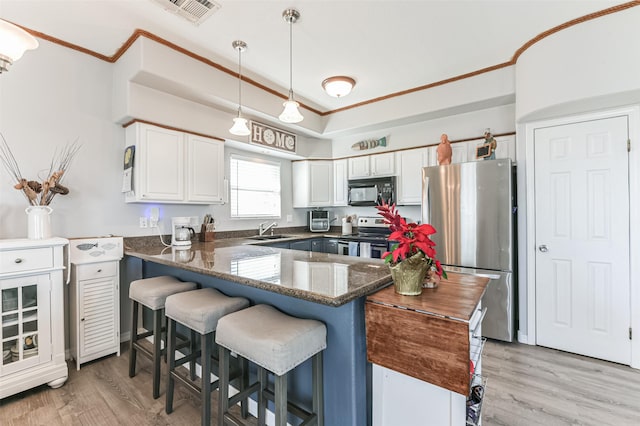 kitchen featuring decorative light fixtures, white cabinetry, appliances with stainless steel finishes, and kitchen peninsula