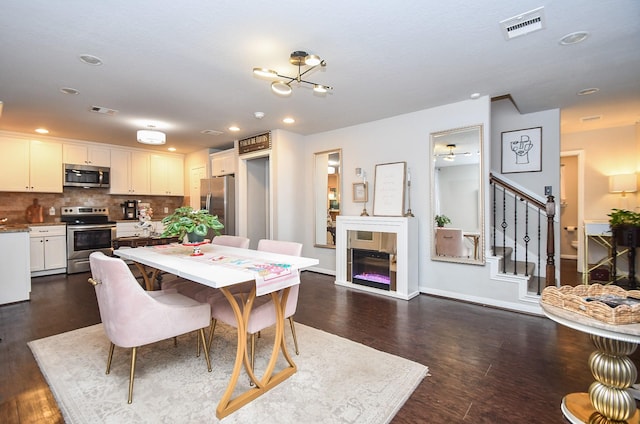 dining space featuring dark hardwood / wood-style flooring and ceiling fan with notable chandelier